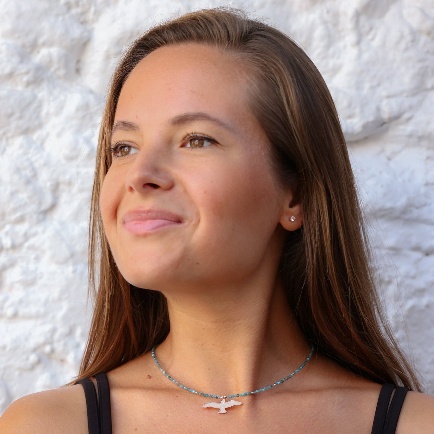 Woman wearing Seagull Apatite Silver Necklace by a white wall