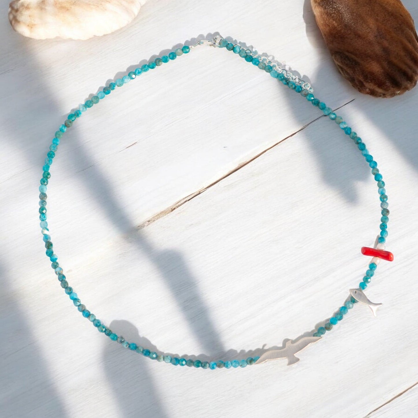 Seagull and Fish Apatite Gemstone Necklace - 925 Silver on a white wooden surface with sea shells.