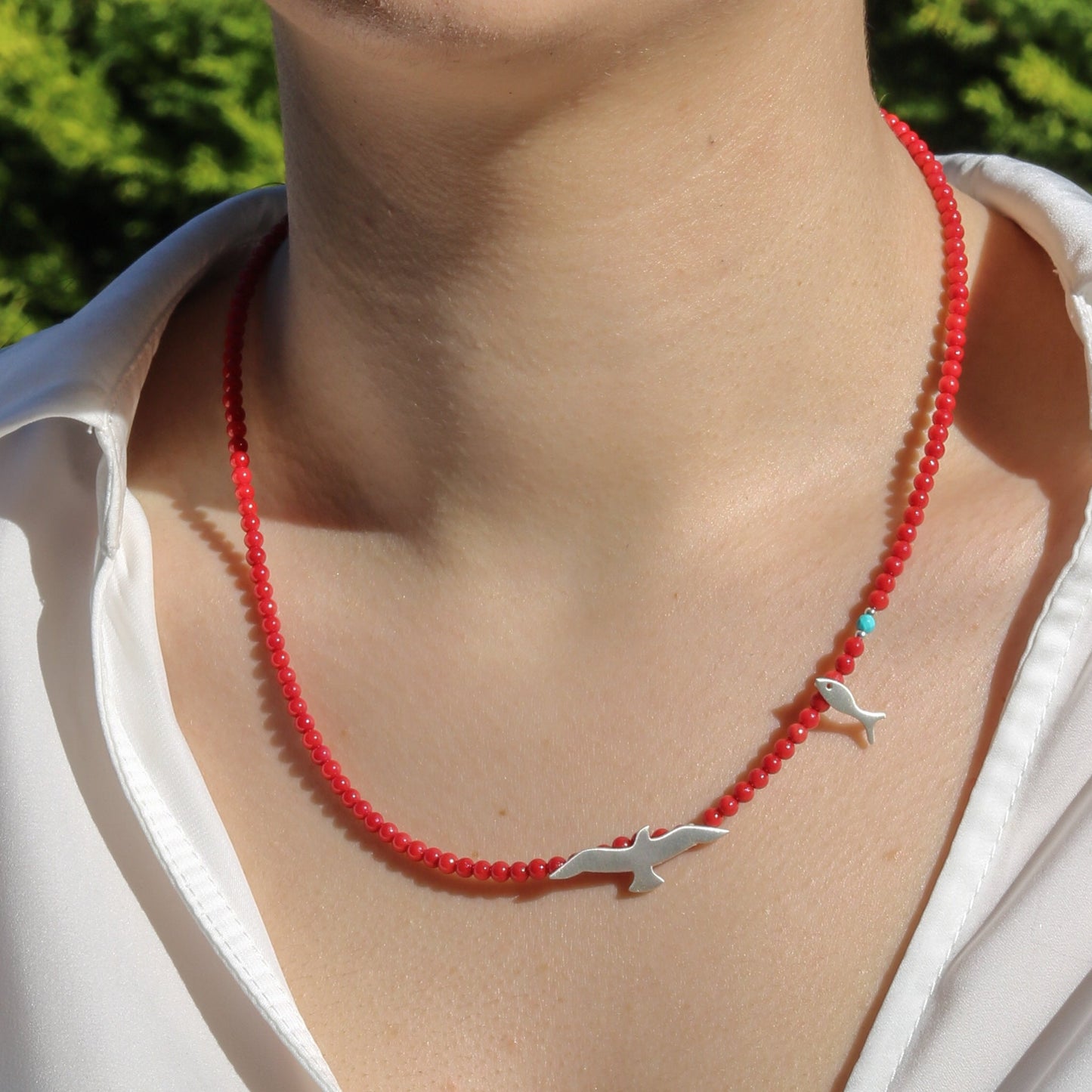 Seagull & Fish Coral and Silver Necklace on a person wearing a white blouse.