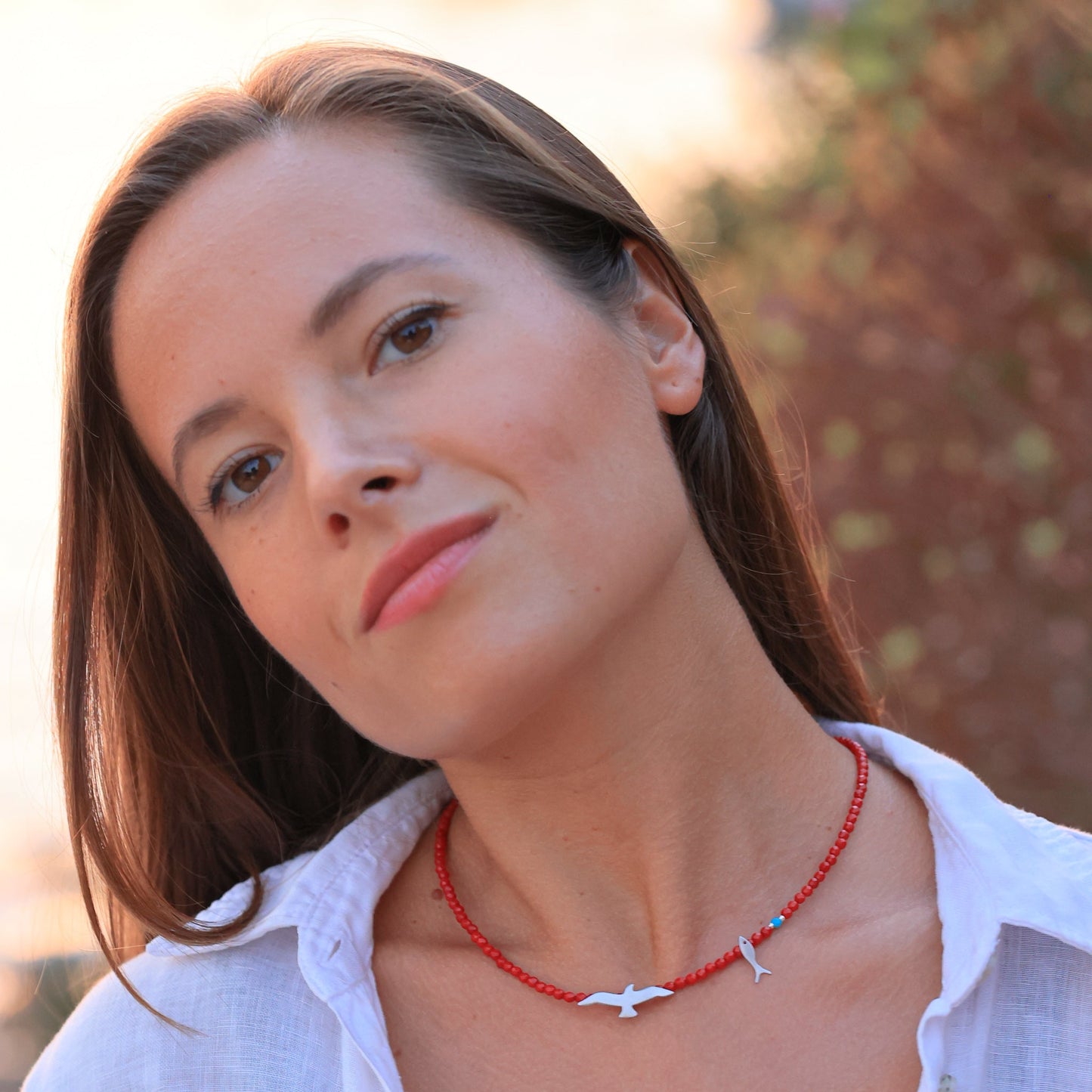 Woman wearing a Seagull & Fish Coral and Silver Necklace with a serene expression.