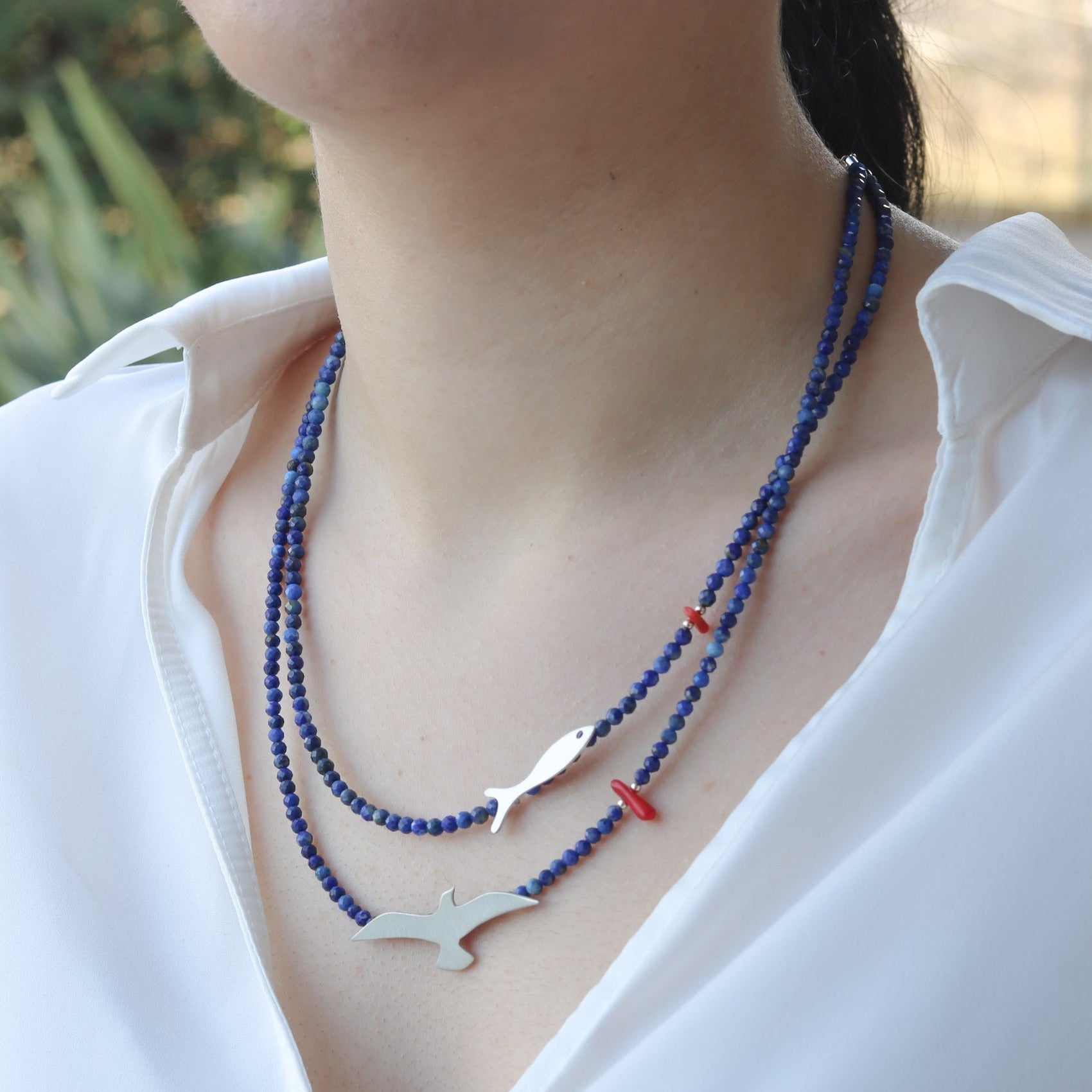 Close-up of Seagull & Fish Lapis and Silver Necklace worn on a woman's neck