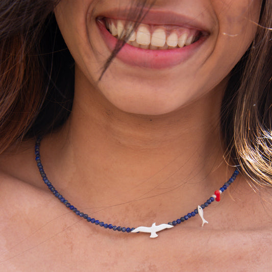 Seagull Lapis Lazuli Gemstone Necklace on woman’s neck, featuring a seagull, fish, and coral charm