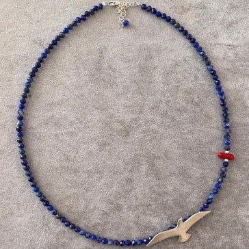 Seagull Lapis Lazuli Gemstone Necklace with bird-shaped pendant on a grey background