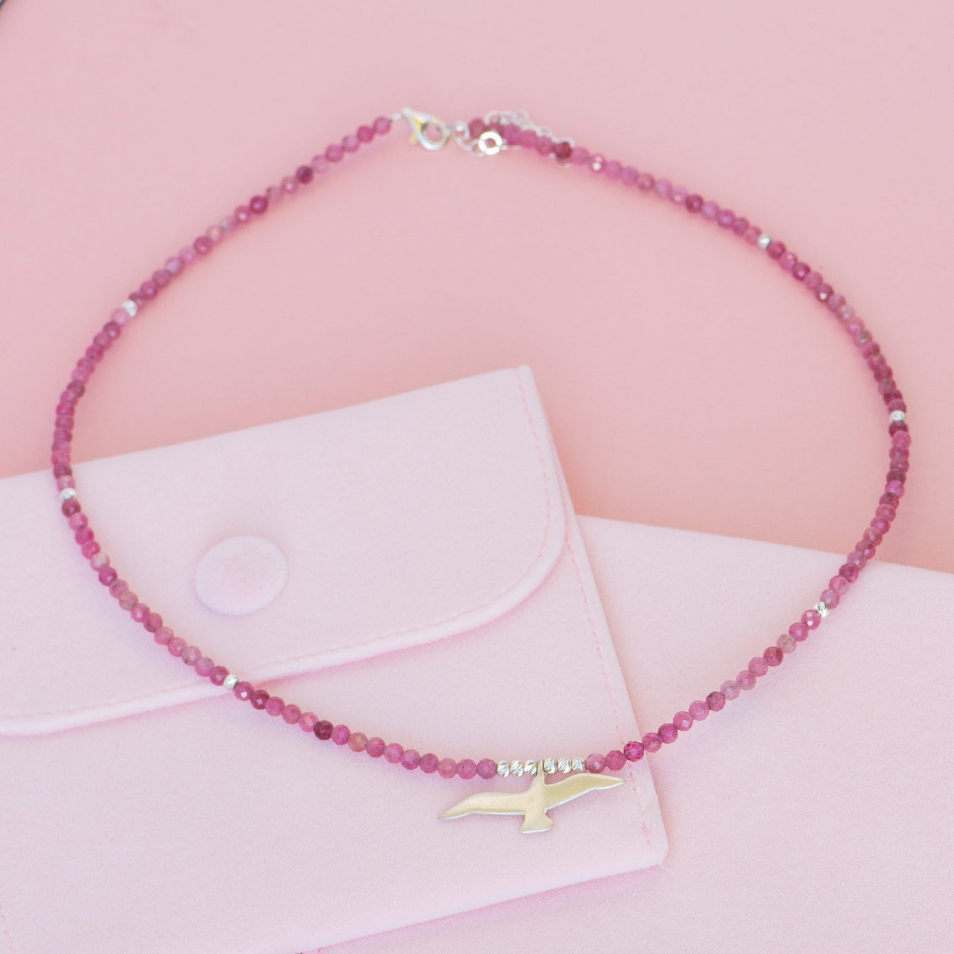 Seagull Pink Tourmaline Necklace displayed on a pink background