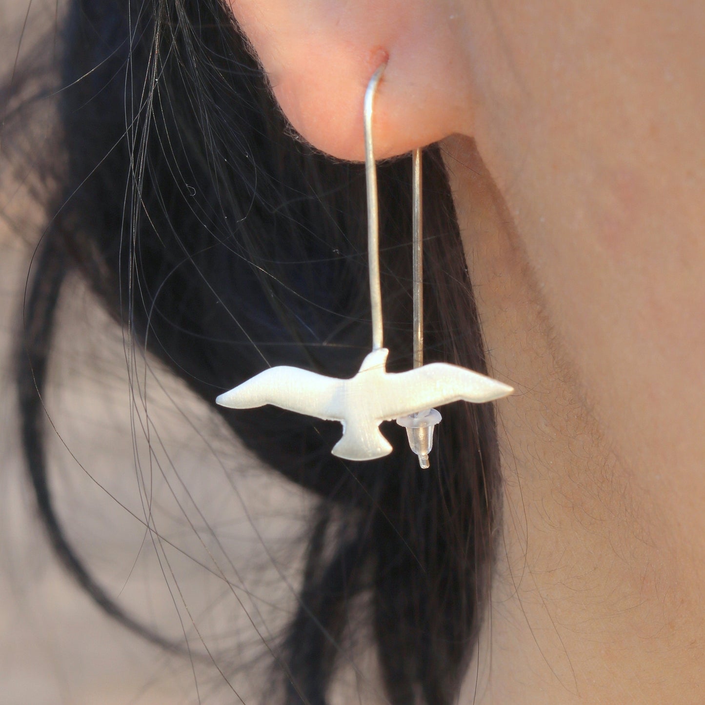 Close-up shot of Seagull Silver Earrings on an ear.