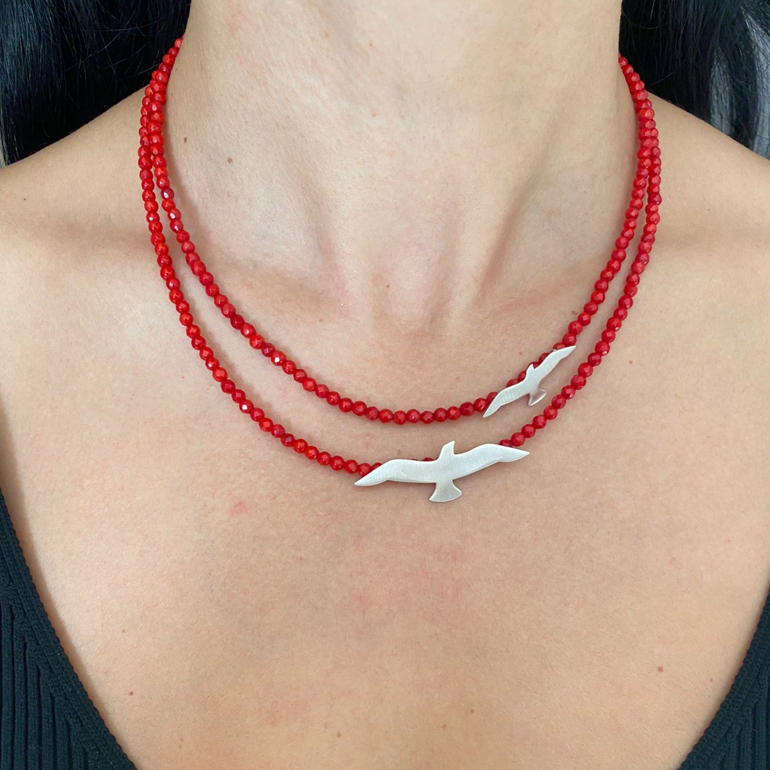 Seagulls Coral Silver Necklace with red beads and silver seagull pendants on a model's neck.