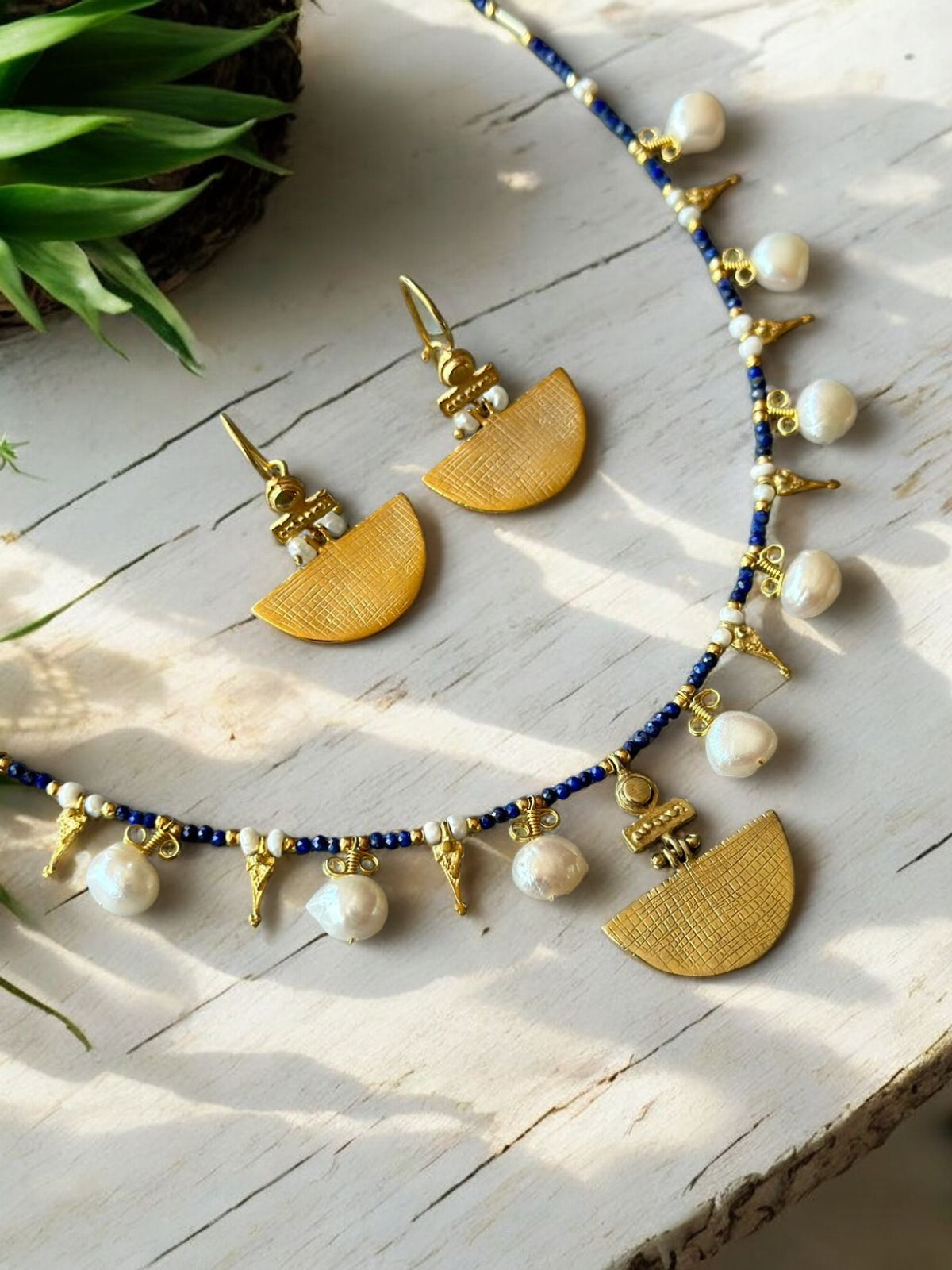 Selena Lapis Lazuli Necklace and Earrings Set - 14K Gold Plated, featuring gold half-moon pendants and white pearls on a white wooden surface.