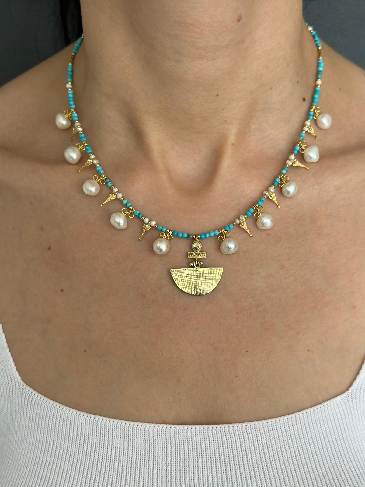 Selena Turquoise Necklace and Earrings Set - 14K Gold Plated with turquoise beads, pearls, and unique gold pendant, worn by a woman.