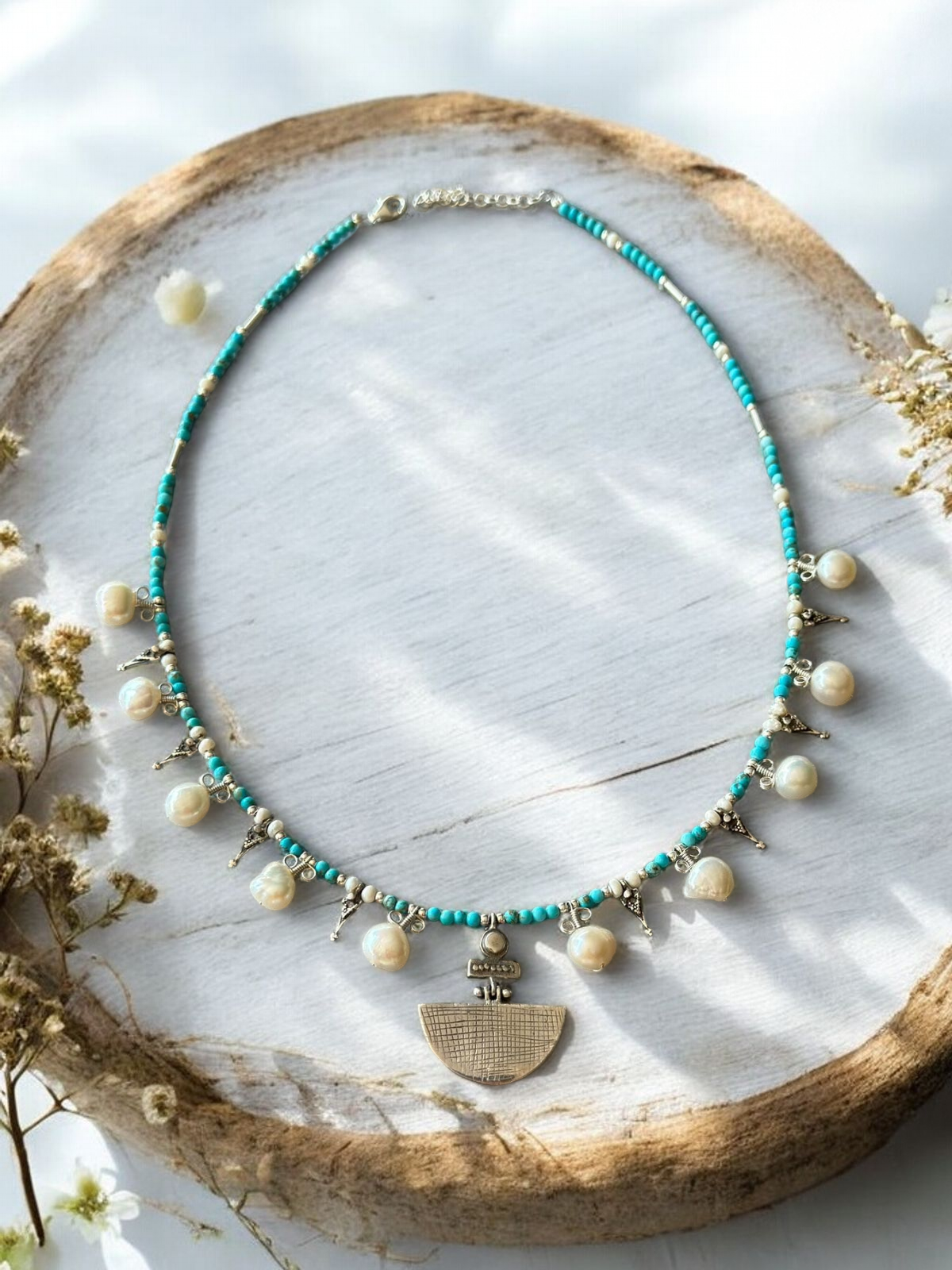 Selene Turquoise Gemstone and Pearl Necklace with delicate silver accents, displayed on a rustic wooden surface