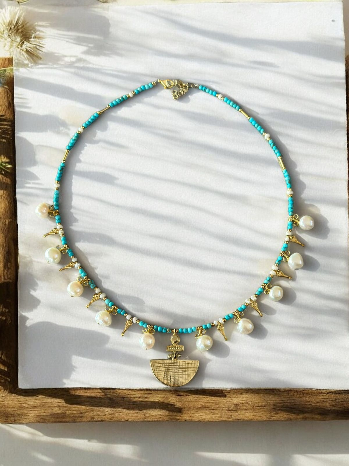 Selene Turquoise Gemstone and Pearl Necklace - Gold Plated displayed elegantly with delicate shadows.