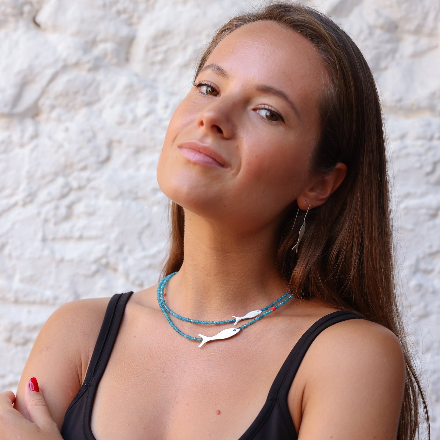 Woman wearing Small and Big Fish Apatite Silver Necklace, featuring blue beads and silver fish charms.