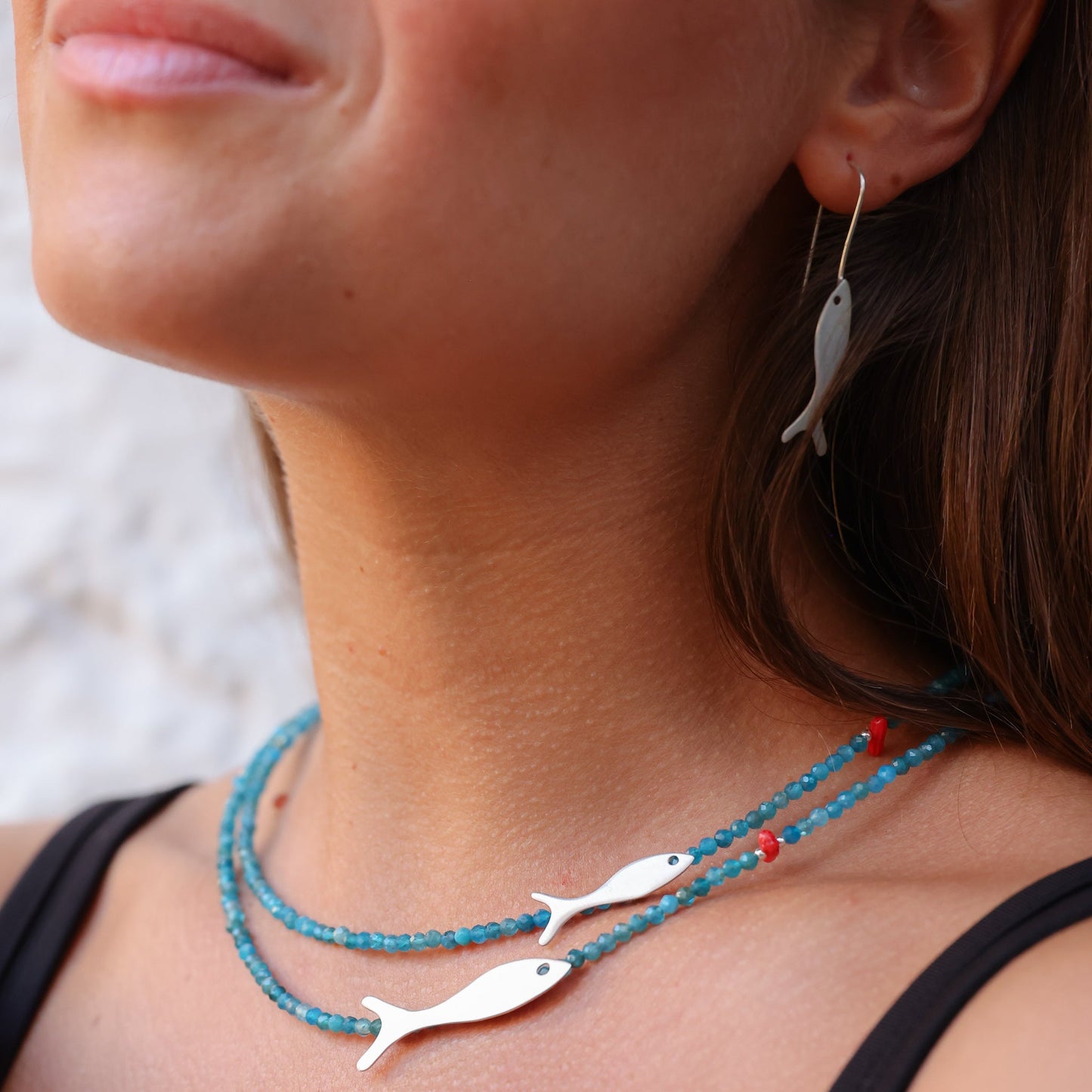 Small and Big Fish Apatite Silver Necklace featured on a woman's neck with matching earrings.