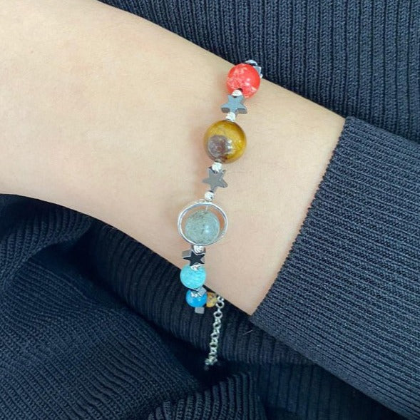 Close-up of a Solar System bracelet featuring colorful planetary beads on a person's wrist.