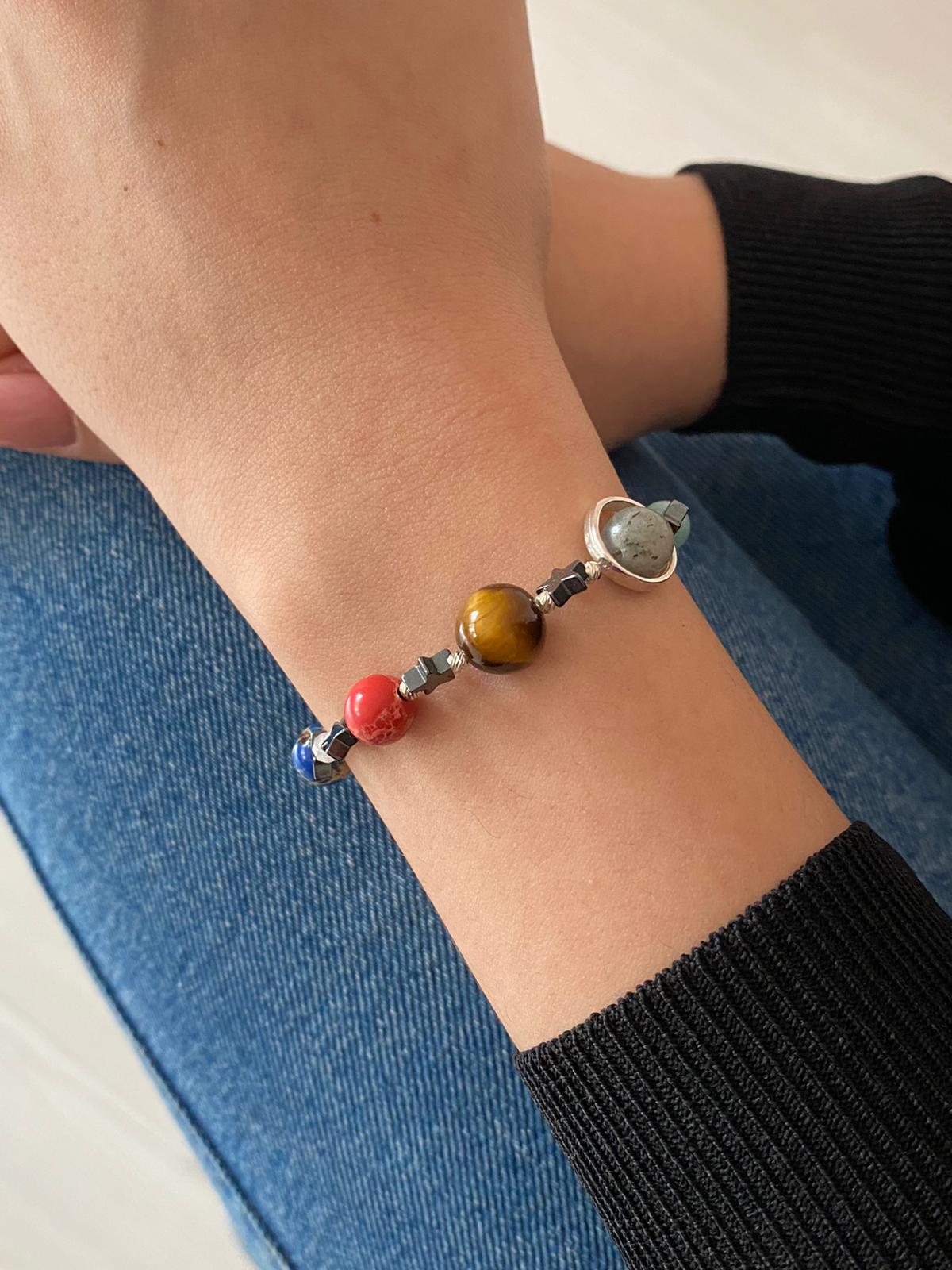 Close-up of wrist wearing a Solar System Bracelet with colorful planet beads.