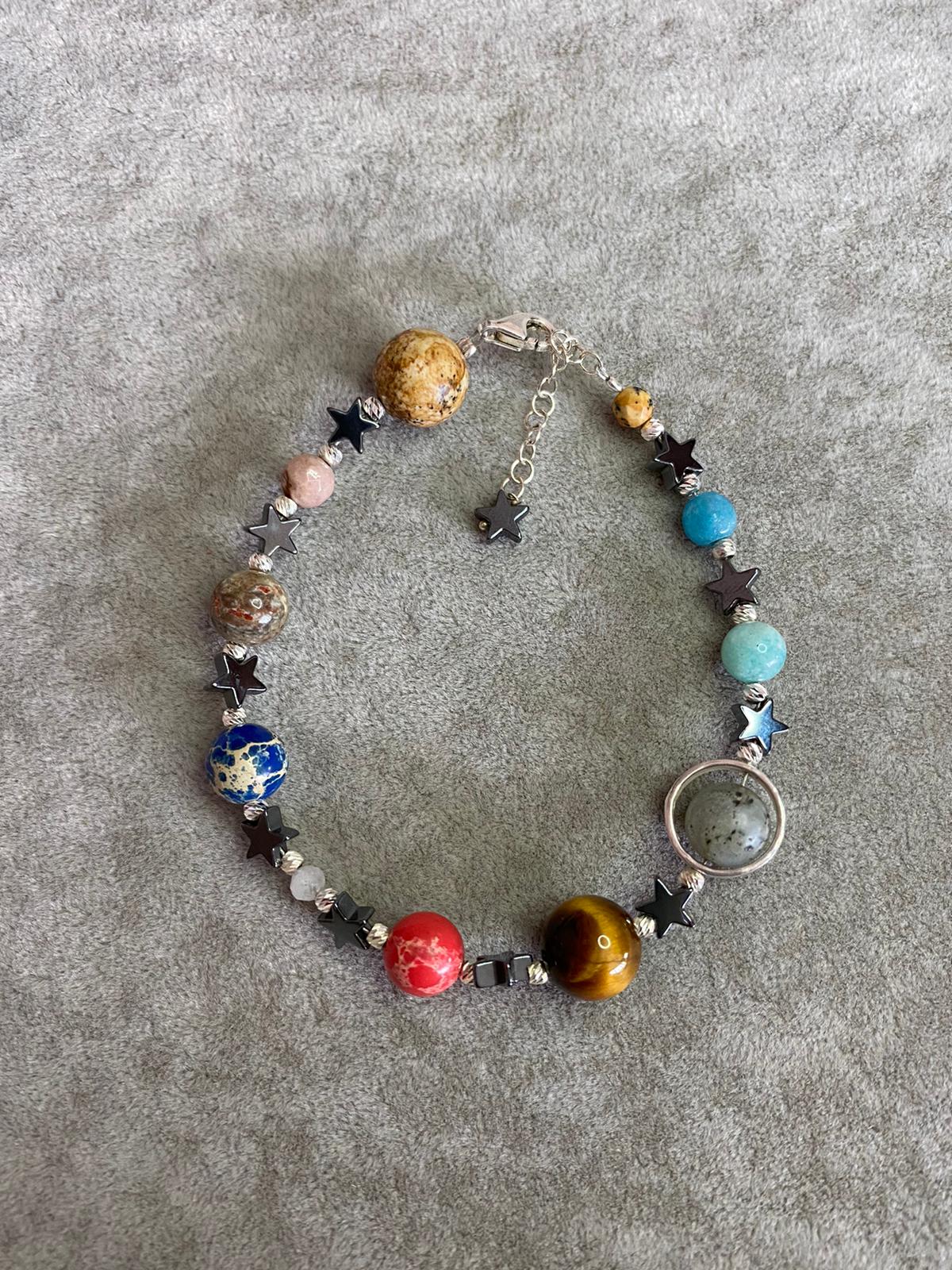 Handcrafted Solar System Bracelet with planets and stars on grey background