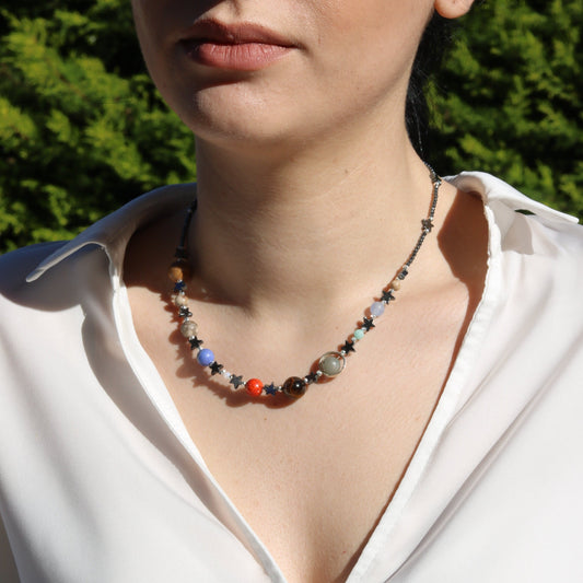 Close-up of a woman wearing a Solar System Necklace featuring colorful planet-like beads