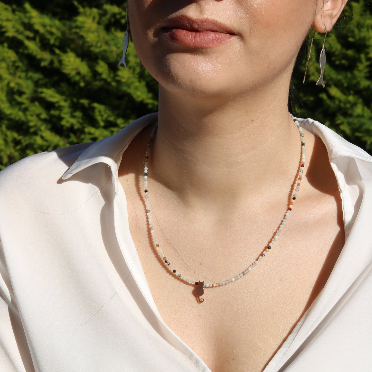 Woman wearing Solo Mini Cat Silver Necklace featuring a delicate cat pendant and colorful beads, paired with a white shirt.