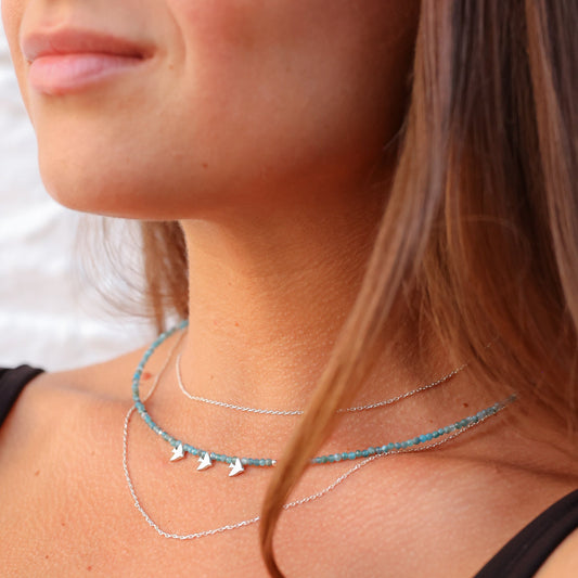 Close-up of woman wearing Trio Birdie Minimal Silver Necklace with turquoise beads and silver bird charms.