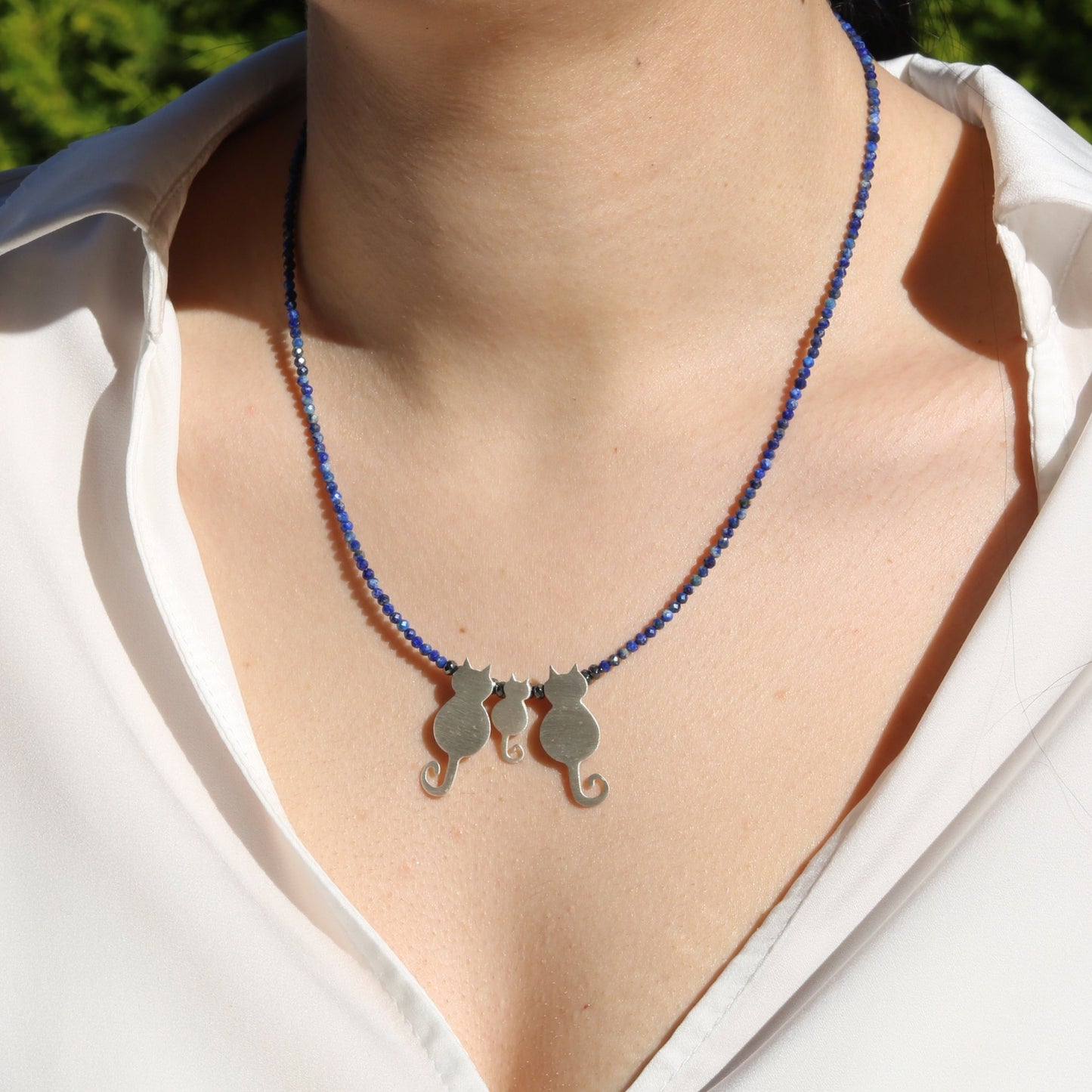 Woman wearing a Trio Cats Family Silver Necklace with blue beads