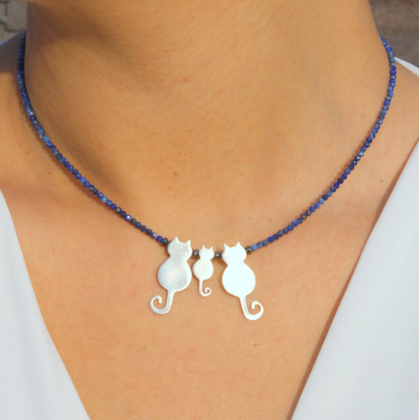 Trio Cats Family Silver Necklace on a blue beaded chain worn by a person