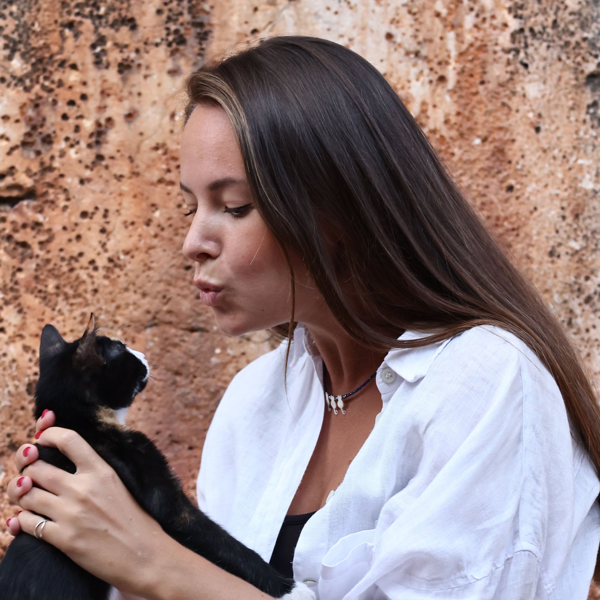 Woman wearing Trio Cats Family Silver Necklace holding a black and white cat