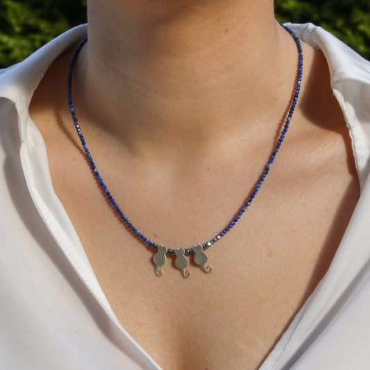 Trio Cats Lapis Silver Necklace displayed on a neck, featuring three cat-shaped silver charms amidst blue lapis beads.