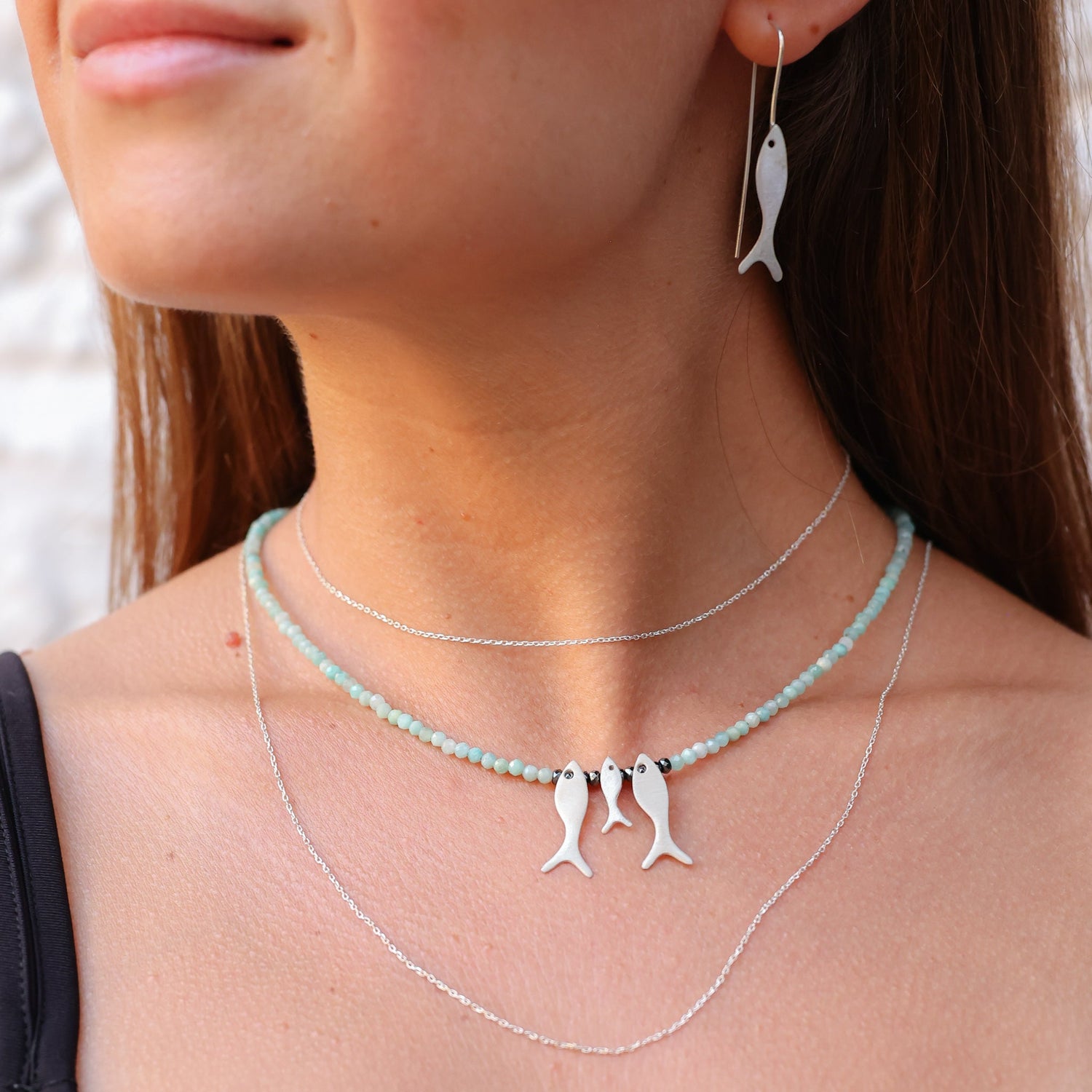 Woman wearing Trio Fish Family Amazonite Necklace with matching fish earrings