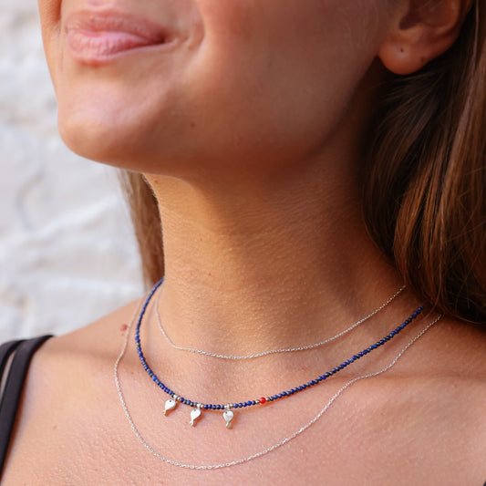 Close-up of Trio Fish Minimal Silver Necklace on woman's neck.